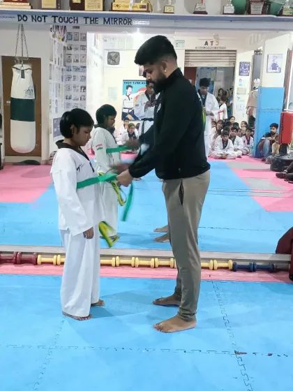 The journey of a thousand miles begins with a single step. Here, I am awarding a new belt to a young student, marking a significant milestone in her Taekwondo training and personal growth.