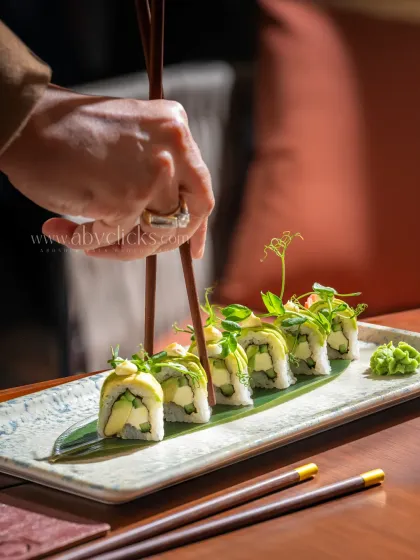 Another angle of the avocado sushi at Camo, with a hand adding a dynamic element to the scene.