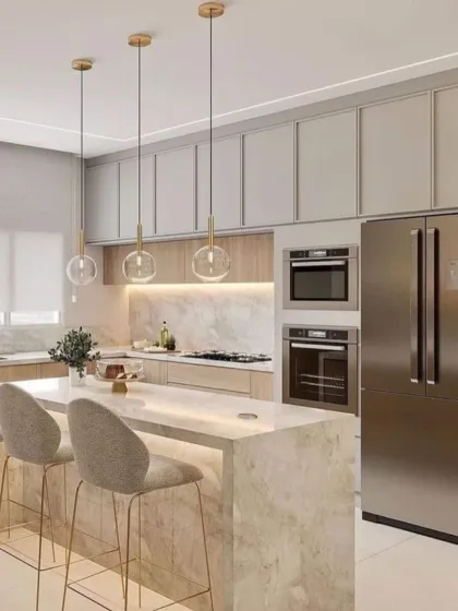 A perfect example of a modern kitchen island that combines form and function. We selected a stunning marble with a waterfall edge for this breakfast bar, complemented by elegant gold-accented pendant lights and built-in appliances for a clean finish.