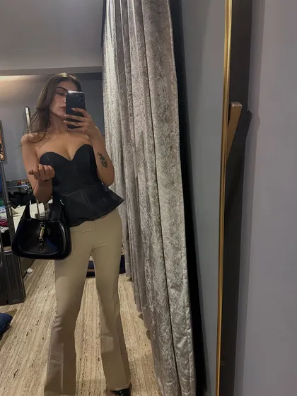 A mirror selfie showing a night-out look. I paired a black corset top with beige flared trousers for a chic and modern silhouette.