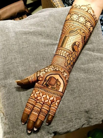 A single-hand view of a detailed bridal arm design, showcasing a doli (palanquin) scene, symbolizing the bride's journey to her new home.