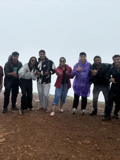 A happy group giving thumbs up at the summit, celebrating their successful trek together.