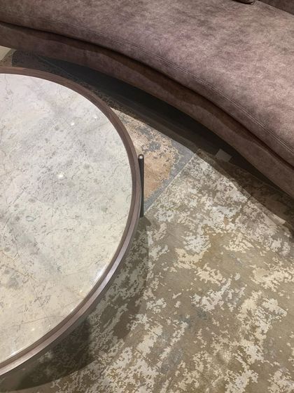 A detail shot showing the sinuous curve of a sofa against the textured floor, a study in form and material.