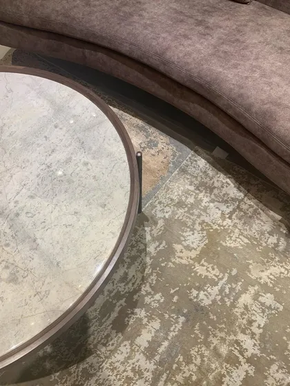 A detail shot showing the sinuous curve of a sofa against the textured floor, a study in form and material.