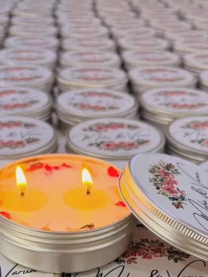 A beautiful shot of our custom tin jar candles, lit to show the double wicks. The lids were personalized with the couple's names, making them a cherished keepsake.