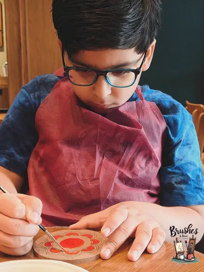 The intense focus of a young boy painting a coaster. I love seeing kids get so lost in the world of colors and patterns.