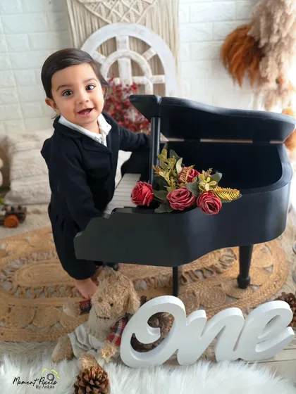 The happiest little pianist. This handsome boy's joyful smile is infectious as he celebrates his first birthday in a stylish black suit.