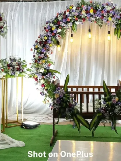 This photo shows the complete stage for a naming ceremony, including the decorative 'aarathi' plate stand. The entire setup is tied together with a beautiful multi-color floral theme.