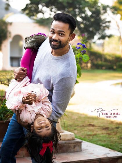 A father playfully holds his daughter upside down during their outdoor family shoot. These are the fun, candid moments that make the best memories.