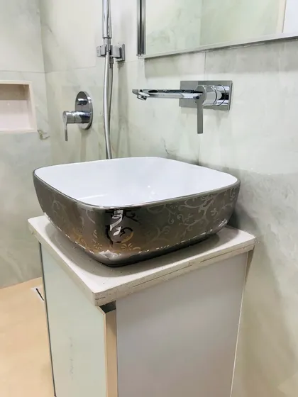 A close-up of the designer vessel sink with a metallic, patterned exterior, sitting atop a clean white vanity cabinet.