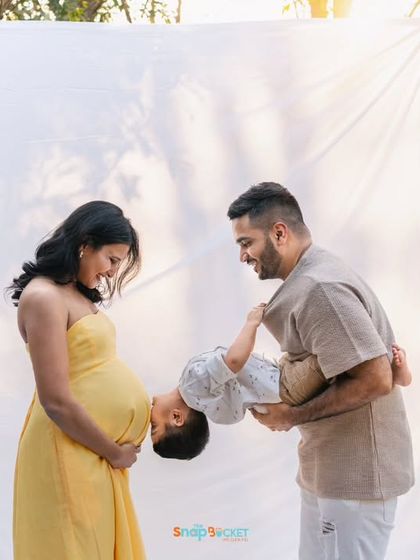 A sweet and playful moment where the older brother leans in to "kiss" his mom's baby bump. It's these unscripted interactions that make for the most memorable maternity photos.