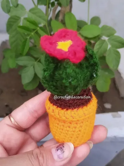 A mini crochet cactus pot with a pink flower on top. This is a perfect, no-maintenance plant for your car dashboard or office desk.