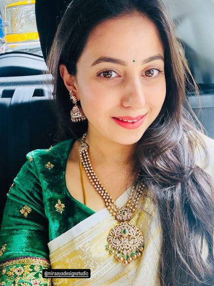 A close-up of a client in a rich green velvet blouse. The delicate gold embroidery adds a touch of luxury to her look.