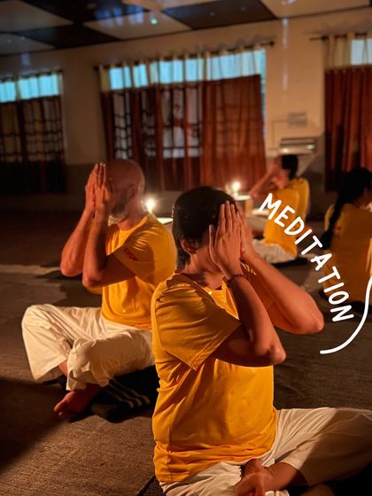 A student practices meditation in the serene, candlelit hall during our yoga vacation. The peaceful atmosphere helps deepen the experience of inner quiet.