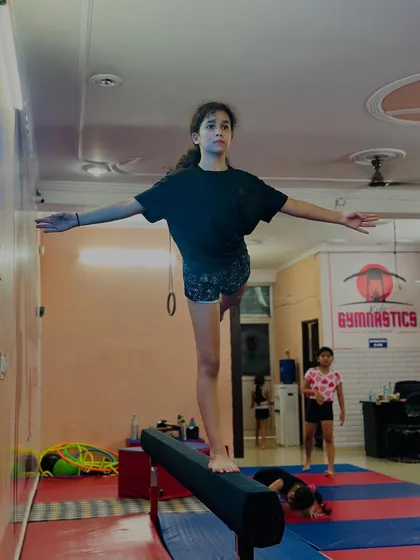 Holding a steady arabesque on the balance beam. This position requires core strength and stability, which are fundamental skills we develop in our gymnasts.