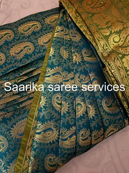A dark teal saree with a gold paisley border.