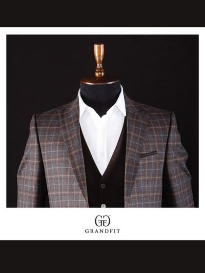 A detailed shot of the brown and blue plaid jacket, focusing on the interplay of colors within the pattern and the sharp cut of the lapels.