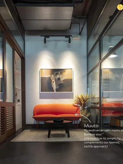 A vibrant orange Muuto sofa adds a pop of color to this lounge area. We believe in balancing our raw, tactile approach with moments of Scandinavian calm and simplicity, creating spaces with a "Bombay soul."