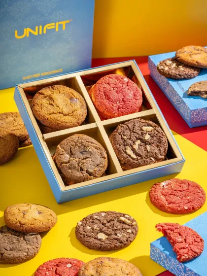 An open gift box of assorted cookies from Unifit, with cookies scattered around to create a fun and abundant scene.