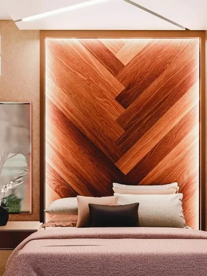 A close-up of the backlit chevron wood headboard, which serves as the stunning centerpiece of this luxurious bedroom design.
