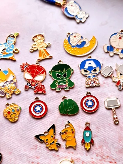 Unwrap joy with these kids' Rakhis featuring all their favorite characters. This image shows a wide variety of enamel charms, including superheroes like Spider-Man and Hulk, and cartoon icons like Doraemon and Pikachu.
