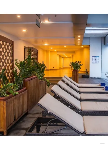 The poolside lounge area of a luxury hotel project in Calicut. This space demonstrates how I extend the landscape experience indoors, using large planters with lush greenery and natural wood trellises to create a tranquil, resort-like atmosphere.