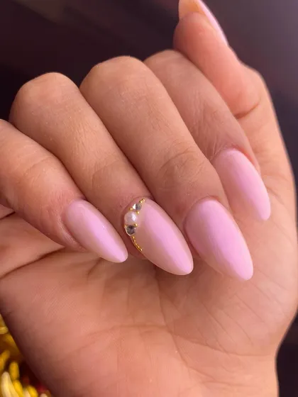 A simple and elegant design in a soft, pearlescent pink. A single accent of gold and pearl at the cuticle adds a touch of understated glamour.