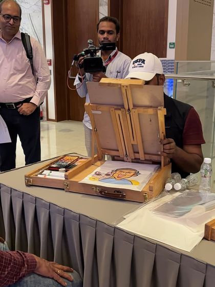 A behind-the-scenes look at my setup at a corporate convention, complete with my wooden easel and art supplies.