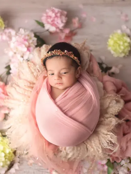 A basket full of sweetness. This baby girl is surrounded by a beautiful arrangement of pink and cream hydrangeas, creating a soft and elegant portrait.
