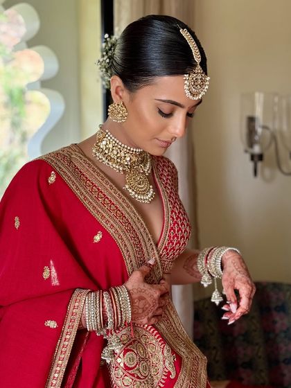 A detailed shot of the bride looking down, showcasing her beautiful eye makeup and the details of her bangles and henna.