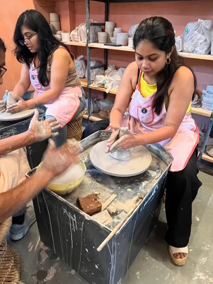 Our instructor providing hands-on guidance to a student, ensuring she gets the feel for shaping the clay on the wheel.