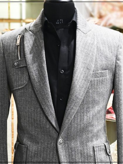 A modern grey blazer with a herringbone pattern and unique zipper details on the lapel. This is a great example of a stylish, semi-formal jacket.