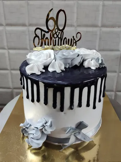 A "60 & Fabulous" cake. This stylish design has a black drip effect over a white base, decorated with grey and white buttercream roses.