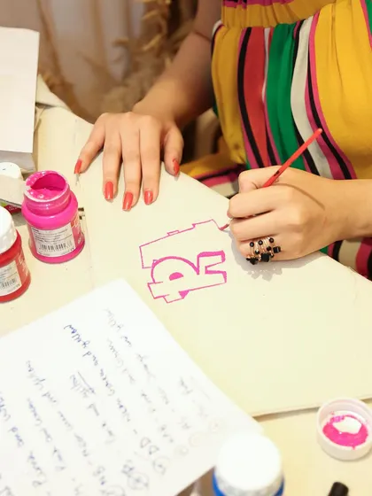 A close-up of me painting a custom initial onto a canvas tote bag at a pop-up event. This kind of on-the-spot personalization is a huge draw and makes for a great guest experience.