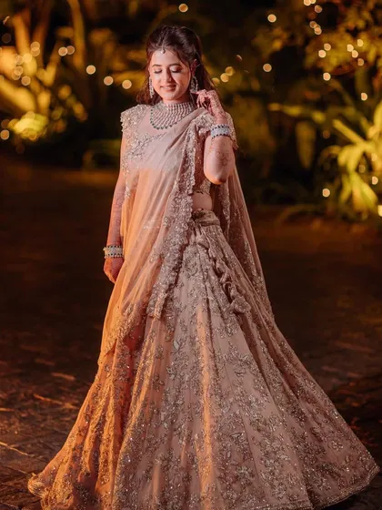 A full view of the bride in her stunning reception outfit, looking every bit the princess in a beautifully lit garden setting.