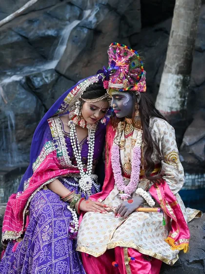 A serene photo of Radha and Krishna by a waterfall.
