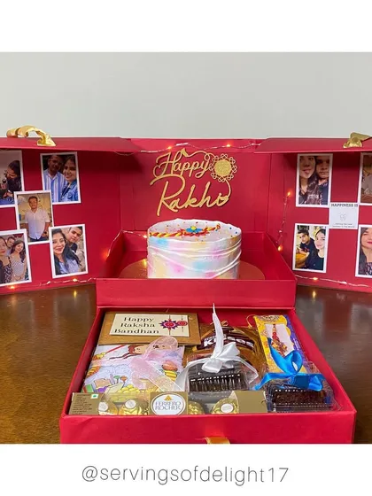 A full view of my Raksha Bandhan Special Gift Hamper Box. You can see the custom cake, the photo-lined walls lit by fairy lights, and the drawer below filled with chocolates, brownies, and a Rakhi.