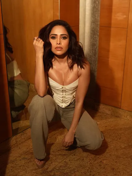 A powerful crouching portrait of Nushrratt Bharuccha, using the warm wood paneling and mirrors of the location to create a moody, reflective atmosphere.
