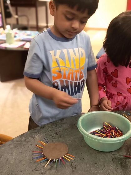 This young boy is carefully selecting sticks for his clay creation. Activities like this build focus and hand-eye coordination.