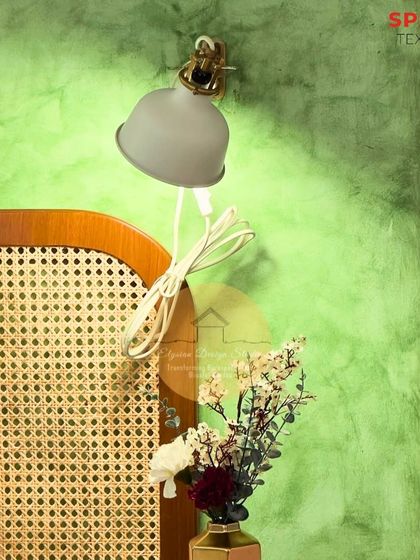 A close-up of the bedside details, including the simple reading lamp, the cane headboard, and the textured green wall, showcasing our focus on craftsmanship and material harmony.