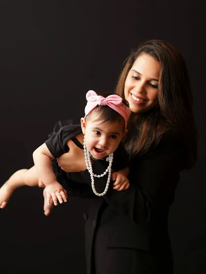 A mother holds her baby girl, who is laughing with delight. This candid shot captures the fun and playful side of motherhood.