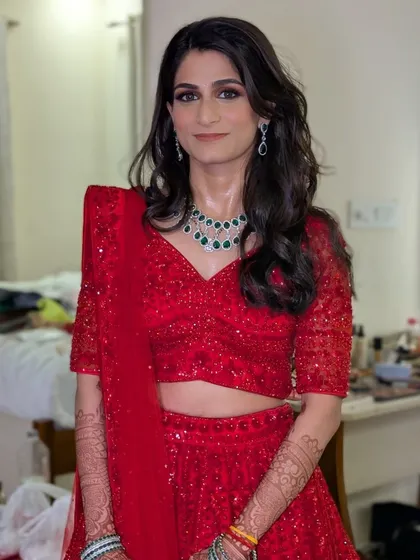 A full view of Shriya's reception look. The sparkling red lehenga paired with a green jade diamond set was a beautiful combination. We chose open, loose waves for her hair to complete this elegant and modern bridal style.
