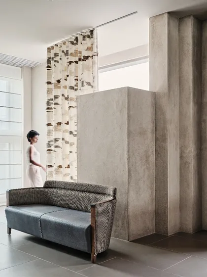 A play of textures and forms inside the Magari store, where a pleated concrete wall contrasts with soft textiles and finely crafted furniture.