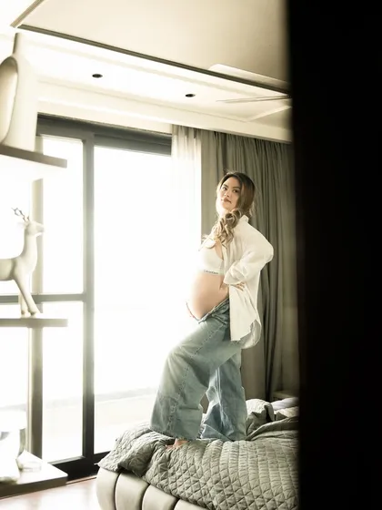 A confident and relaxed pose on the bed during an in-home session, bathed in beautiful natural light.