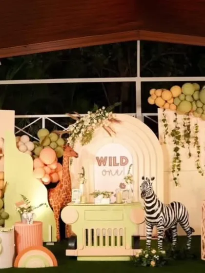 I bring the jungle to you with this "Wild One" safari-themed first birthday party. This expansive setup includes life-sized animal cutouts like a zebra and elephant, custom backdrops with giraffe prints, and lush green and earthy-toned balloon arrangements to create an immersive adventure for your little explorer.