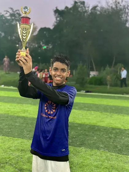 Lifting the trophy high. This player celebrates his team's victory with a huge smile.