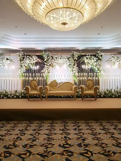 This stage design embodies pure elegance for a classic reception. We combined grand Victorian-style seating with a modern backdrop of cascading white florals and hundreds of warm, glowing candles to create a truly romantic focal point.
