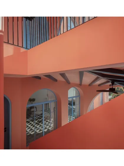 The interlocking forms and levels of the Baia Villas create a complex and engaging journey through the space. This view captures the relationship between the upper balcony and the ground-floor veranda, connected by the unifying peach facade.