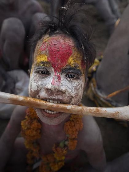 A young boy with his face painted participates in Masaan Holi in Varanasi, holding a bone in a ritual that playfully defies death.