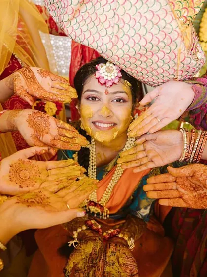 The bride's hands being covered in turmeric paste by her loved ones. A beautiful, intimate moment from the Haldi ceremony.